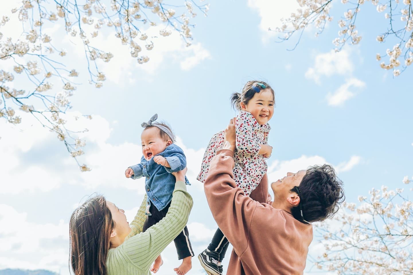 青空バックに高い高いされる子供と親