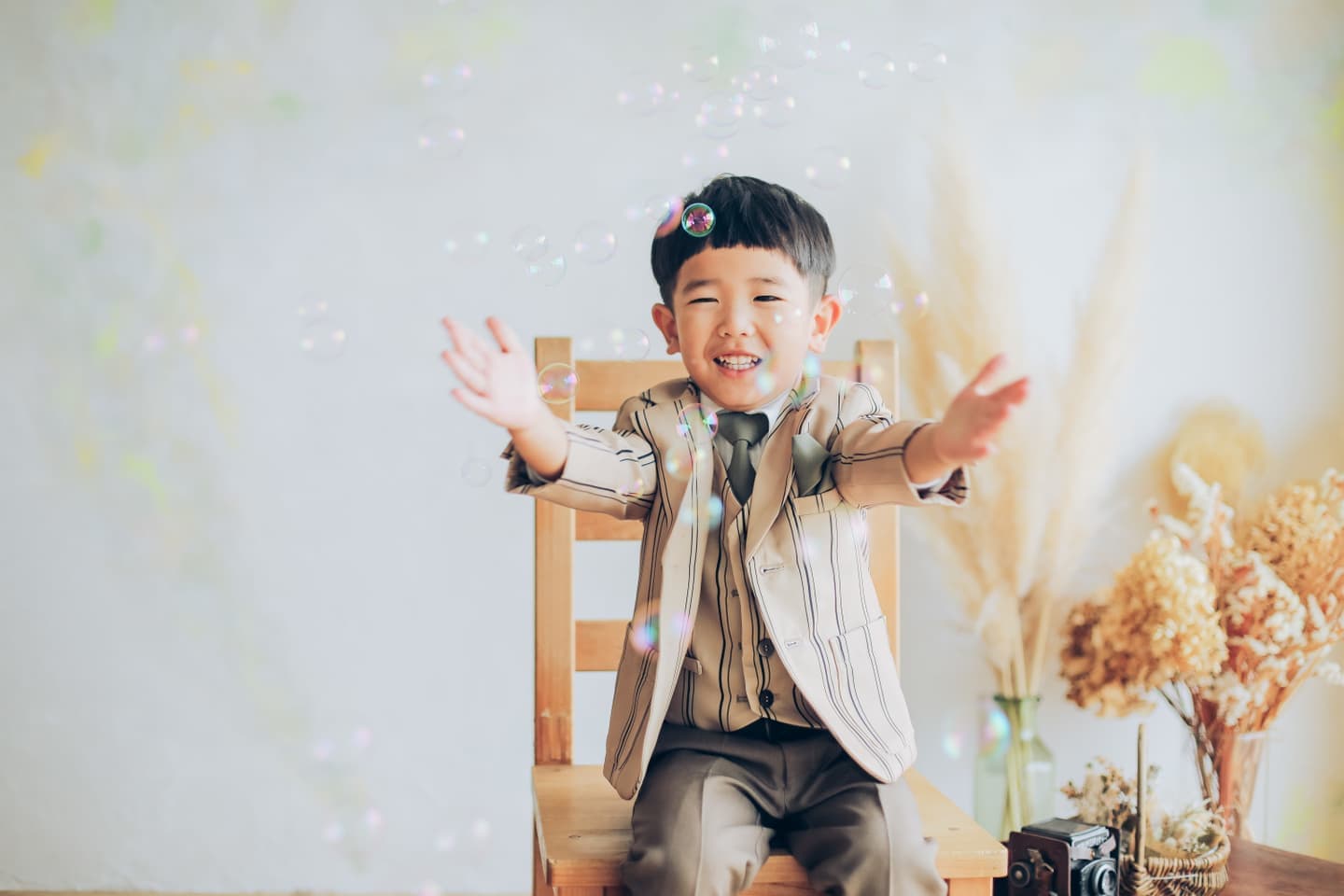 ストライプの服を着てシャボン玉を叩こうとする男の子