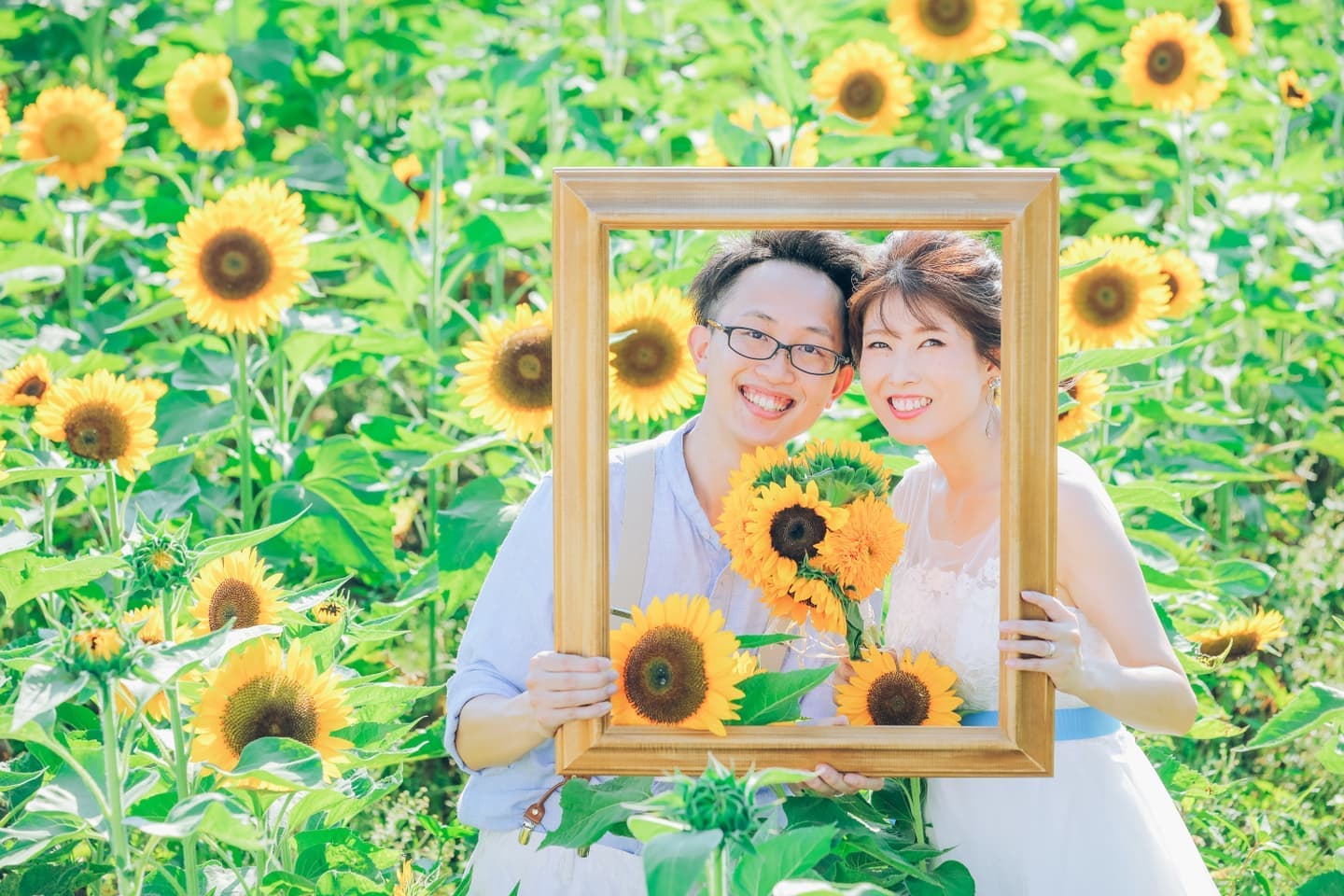 ひまわり畑で額から顔を出す男女