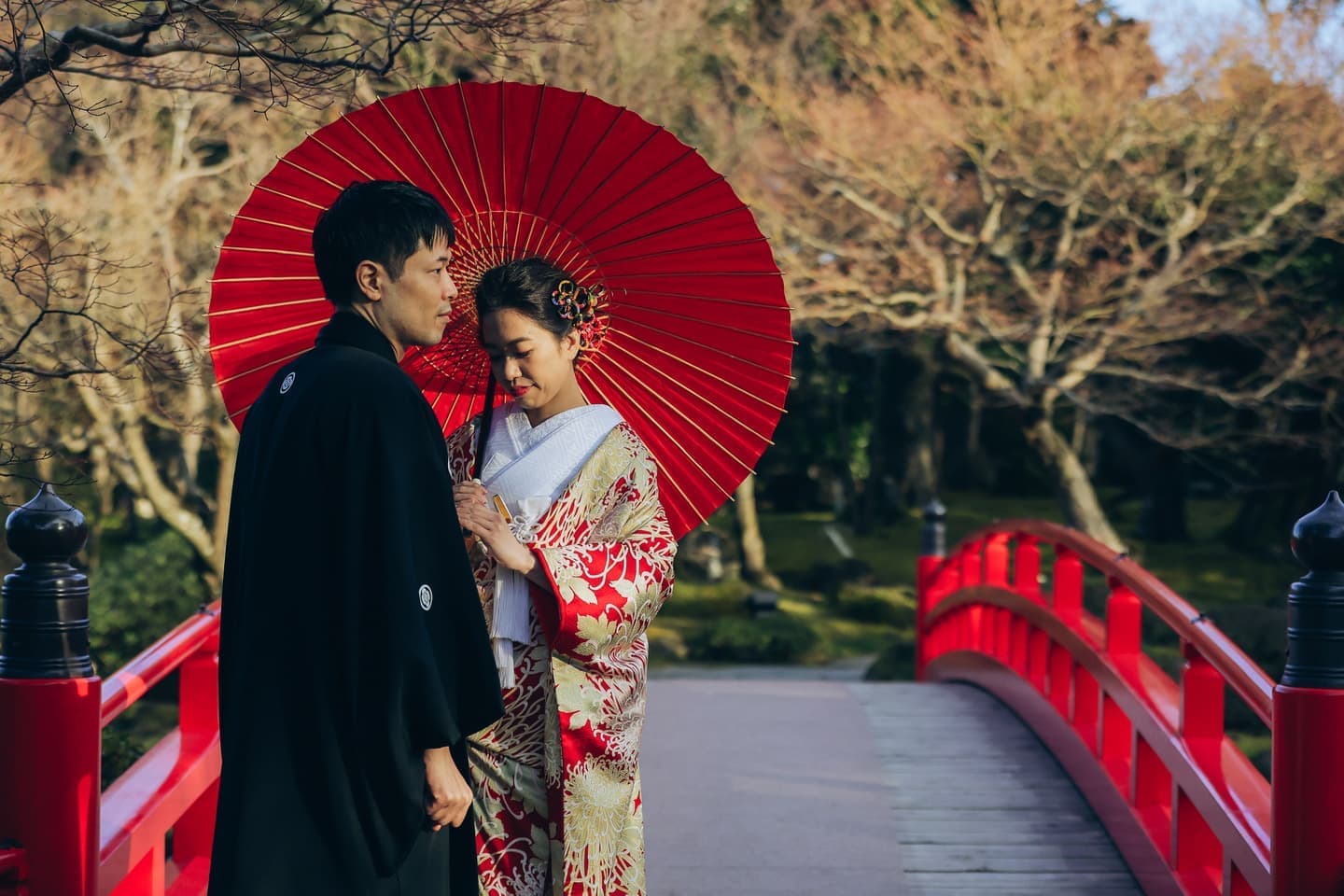 赤い傘をさし和装した男性と女性