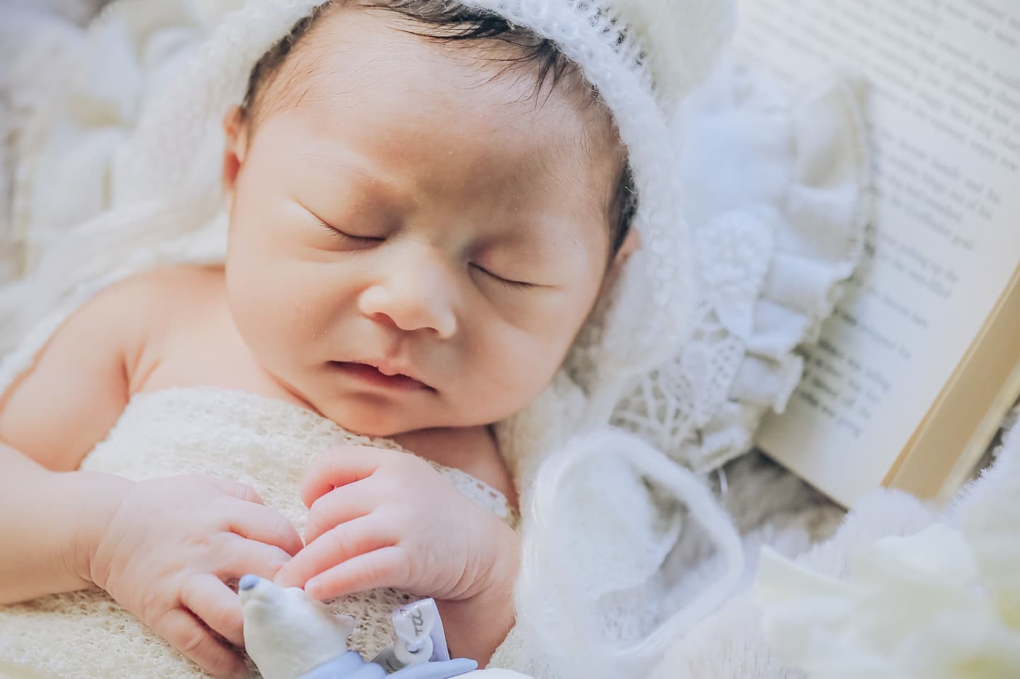 本を枕に眠る新生児