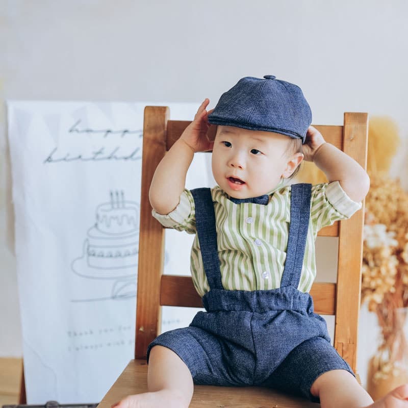 ジーンズ生地の帽子とストライプのシャツにジーンズのパンツを合わせた男の子
